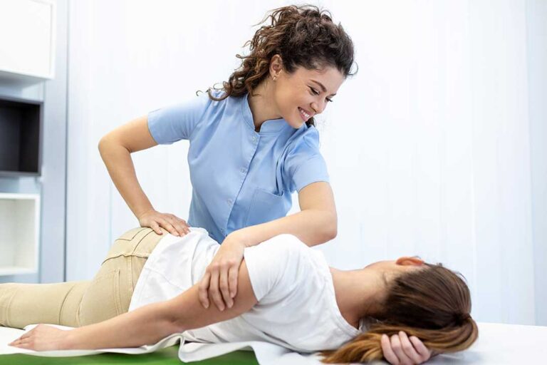A chiropractor carefully checking a young child's back as the child sits calmly on an exam table.